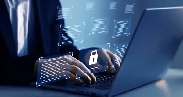 Mains sur un ordinateur portable entouré de documents et d’un cadenas numériques