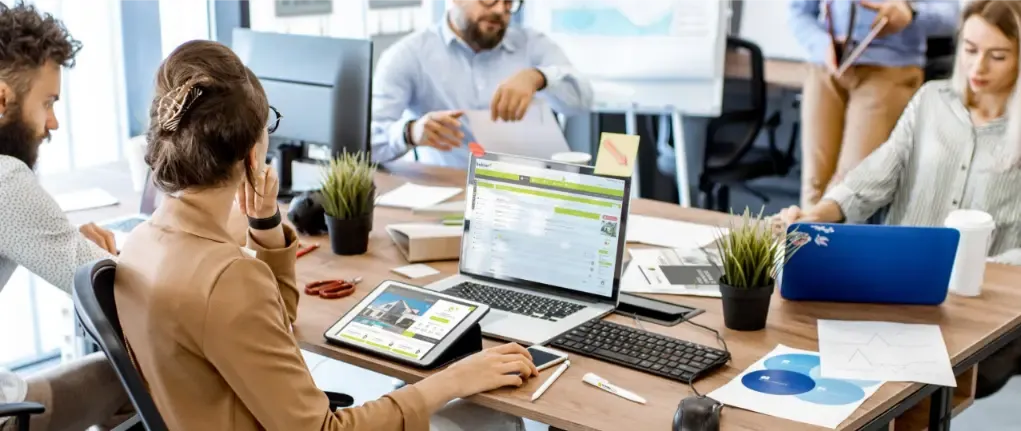 Équipe métier travaillant sur ordinateurs et tablettes autour d’une table